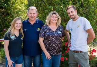 Vier lachende mensen staan bij het groen aan Flower Camping Le Pont du Tarn in Occitanië, Frankrijk.