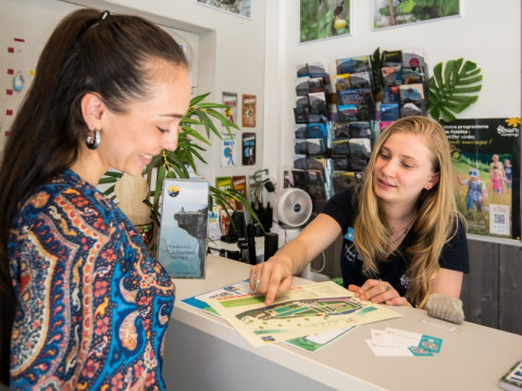 Receptioniste helpt gast met kaart bij Flower Camping Le Pont du Tarn vakantiepark in Occitanie, Frankrijk.