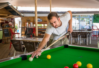 Man speelt biljart aan een tafel in de buitenruimte van Flower Camping Le Pont du Tarn in Occitanië, Frankrijk.
