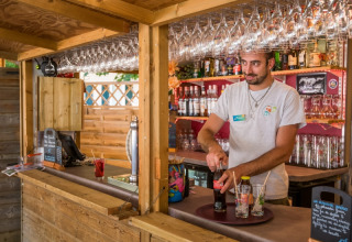 Ein Barkeeper bereitet Getränke in einer Holzbar im Flower Camping Le Pont du Tarn in Okzitanien, Frankreich zu.