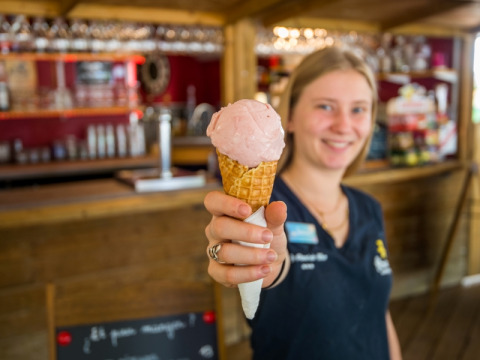 Eine freundliche Mitarbeiterin im Flower Camping Le Pont du Tarn, Occitanie, Frankreich, reicht ein Eis.