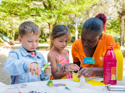 Kinderen doen knutselwerkjes met een volwassene op Flower Camping Le Pont du Tarn, een vakantiepark in Occitanië, Frankrijk.