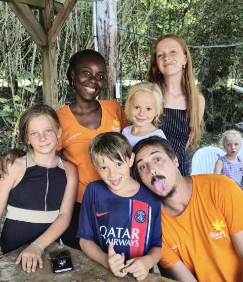 Group of smiling children and adults posing outdoors at Flower Camping Le Pont du Tarn in Occitanie, France.