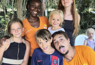 Group of smiling children and adults posing outdoors at Flower Camping Le Pont du Tarn in Occitanie, France.