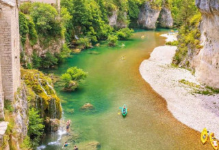 Menschen paddeln in Kanus auf einem klaren Fluss bei Florac-Trois-Rivières, Occitanie, umgeben von Felsen.