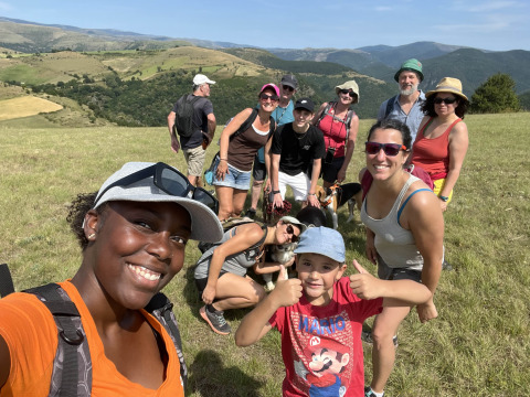 Group of people enjoying a sunny outdoor day at Flower Camping Le Pont du Tarn in Occitanie, France, with hills behind.