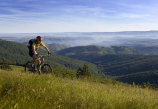Mountainbiker geniet van het uitzicht op heuvels bij Flower Camping Le Pont du Tarn in Occitanië, Frankrijk.
