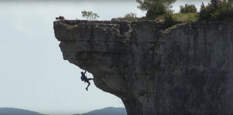 A climber ascends a steep cliff while a photographer shoots from above at Flower Camping Le Pont du Tarn, France.
