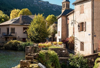 Scenic village near Florac-Trois-Rivières, Occitanie, France, with a river, old houses, and mountain views.