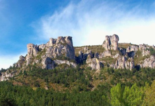 Klipper og frodige bakker nær Florac-Trois-Rivières i Occitanie, Frankrig, under en blå himmel.