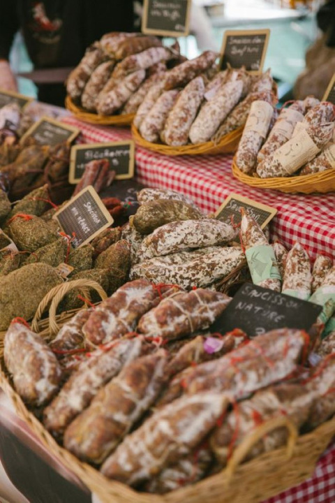 Französischer Markt bei Florac-Trois-Rivières mit Körben voller getrockneter Würste auf rot-weißem Tuch.
