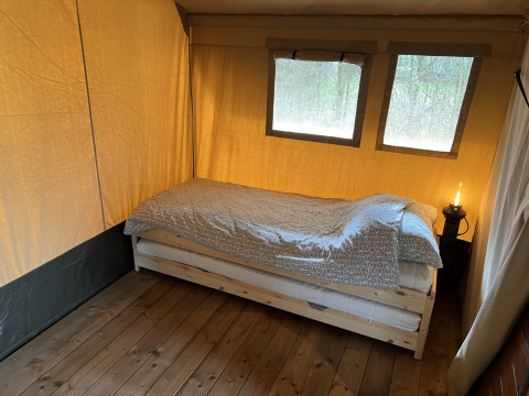 En enkel seng i et safari telt på Camping 'de Val' i Holland, med træ gulv og naturligt lys.