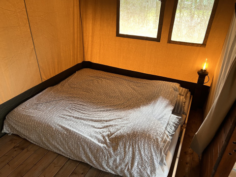 Innenaufnahme eines Safari-Zeltes mit Doppelbett und Nachttischlampe auf Camping 'de Val' in den Niederlanden.