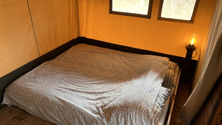 Innenaufnahme eines Safari-Zeltes mit Doppelbett und Nachttischlampe auf Camping 'de Val' in den Niederlanden.