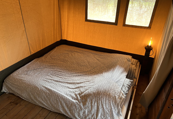Indvendigt billede af en safari-telt med en dobbeltseng og natlampe på Camping 'de Val' i Holland.