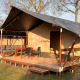 Tienda safari en Camping 'de Val', Países Bajos, con porche de madera y muebles de jardín al sol.