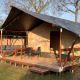 Safari-telt ved Camping 'de Val' i Holland med træveranda, havemøbler og udendørs siddeplads i solen.