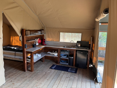 Interieur van een safaritent met ingerichte keuken bij Camping 'de Val' in Nederland.