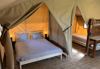 Interno di una tenda safari con letto matrimoniale e singolo al Camping 'de Val' nei Paesi Bassi.