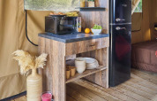 Angolo cucina accogliente in una tenda safari al Kenya Lodge, Flower Camping Le Pont du Tarn, Francia, con frigo e microonde.