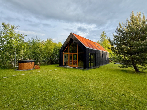 Forest villa De Bosburcht met sauna, moderne lodge omringd door grasveld en bomen in de natuur.