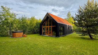 Forest villa De Bosburcht avec sauna, maison moderne entourée de verdure et grand jardin herbeux.