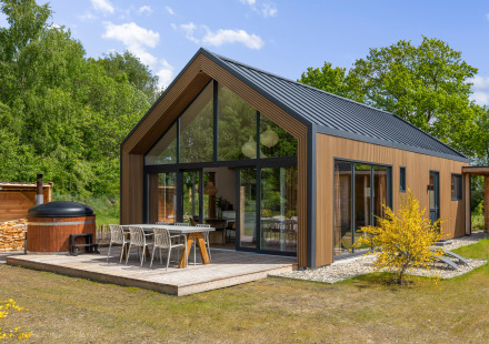 Forest villa Heidehaas met hot tub, moderne houten gevel, grote ramen en terras midden in de natuur.