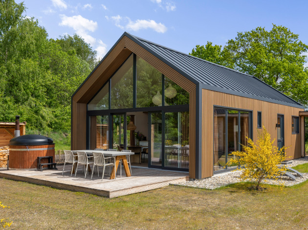 Forest villa Heidehaas met hot tub, moderne houten gevel, grote ramen en terras midden in de natuur.