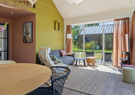 Moderne woonkamer in Forest villa «Heidehaas» bij De Kremmer, Nederland, met grote glazen ramen.