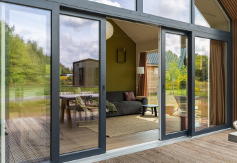 Zicht door grote glazen deuren op het moderne salon van Forest villa «Heidehaas» bij De Kremmer, Nederland.
