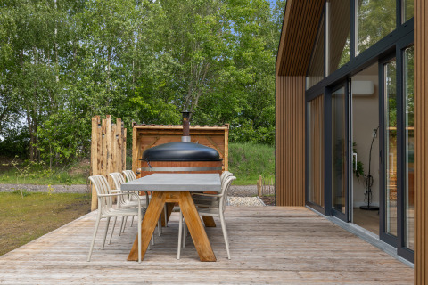 Buitenterras van Forest villa «Heidehaas» in De Kremmer, Nederland, met eettafel, stoelen en bosuitzicht.