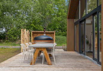 Terraza exterior de la Forest villa «Heidehaas» en De Kremmer, Países Bajos, con mesa, sillas y vista al bosque.