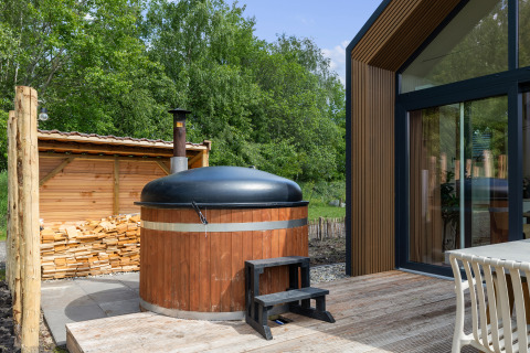 Houten hottub met zwart deksel op het terras bij Forest villa «Heidehaas» te De Kremmer, Nederland.
