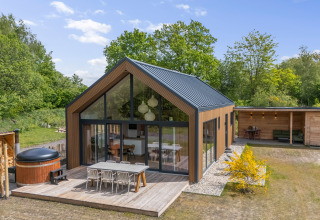 Moderne houten forest lodge met terras bij Forest villa «Heidehaas» te De Kremmer, Nederland, zonnig.