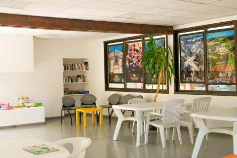 Gemeenschapsruimte bij Onlycamp Camping de l'Argenté in Occitanie met boeken, tafels en kleurrijke affiches.