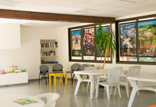 Gemeenschapsruimte bij Onlycamp Camping de l'Argenté in Occitanie met boeken, tafels en kleurrijke affiches.