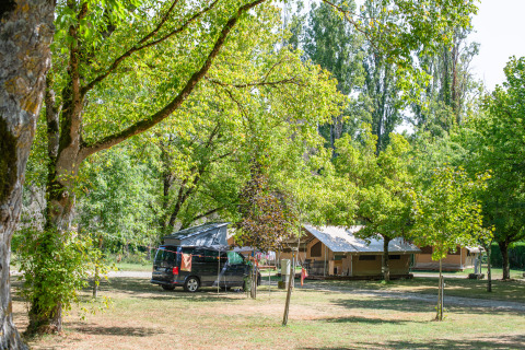 Tente safari Ponza et van campeur sous des arbres verts au Onlycamp Camping de l'Argenté en France, ambiance naturelle paisible.