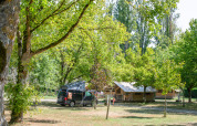 Tente safari Ponza et van campeur sous des arbres verts au Onlycamp Camping de l'Argenté en France, ambiance naturelle paisible.