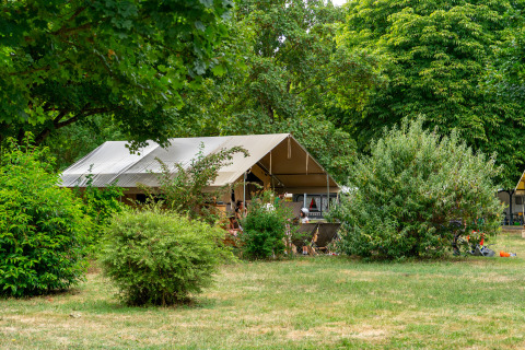 Tente safari Ponza au Onlycamp Camping La Gâtine en France, entourée de verdure et d’arbres feuillus.