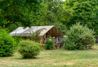 Tente safari Ponza au Onlycamp Camping La Gâtine en France, entourée de verdure et d’arbres feuillus.