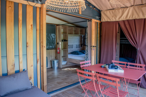 Interior de tienda safari con mesa de comedor roja, sillas y dormitorio doble cómodo y moderno.