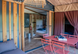 Interior de tienda safari con mesa de comedor roja, sillas y dormitorio doble cómodo y moderno.