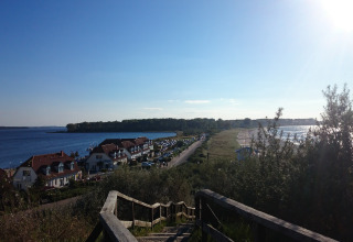 Uitzicht vanaf een trap bij Am Strand lodge in Duitsland met huizen, strand en zee onder blauwe lucht.