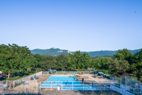 Piscina exterior en Onlycamp Camping Les Tuillères, rodeada de árboles y montañas en Auvergne-Rhône-Alpes.