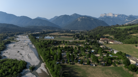 Vista aérea de los alrededores de Vercheny, Auvernia-Ródano-Alpes, Francia, con río y montañas de fondo.