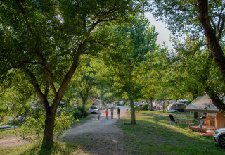 Camping Onlycamp Les Tuillères in Auvergne-Rhône-Alpes, Frankrijk, met bomen, tenten en wandelaars.