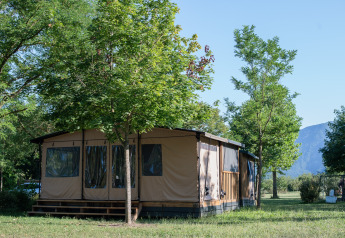 Tenda safari Galli Tiny-house presso Onlycamp Camping Les Tuillères in Francia, circondata da alberi e natura verde.