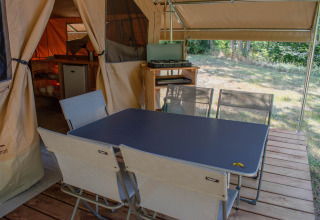 Buiten eetplek bij een Ponza safaritent op Onlycamp Camping Les Tuillères in Frankrijk met tafel en stoelen.
