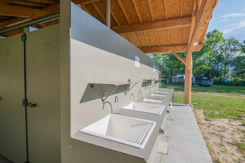 Outdoor dishwashing sinks at Onlycamp Camping Chamarges holiday park in Auvergne-Rhône-Alpes, France.