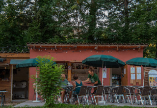Buitencafé bij Onlycamp Camping Chamarges in Auvergne-Rhône-Alpes, Frankrijk, met klanten en parasols.
